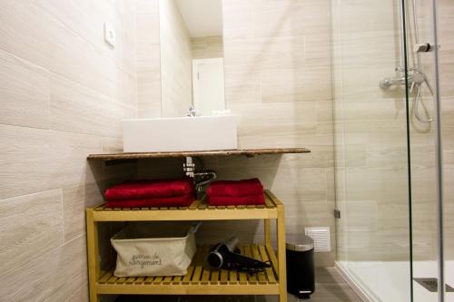 a bathroom with red towels and a sink and a shower at MS Apartamentos, Setúbal in Setúbal