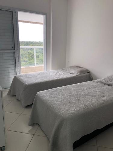 2 camas en una habitación blanca con ventana en Condominio Reserva da Mata - Riviera de São Lourenço, en Riviera de São Lourenço