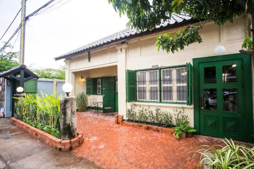 a house with green doors and a red brick walkway at Barn1920s Hostel in Vientiane