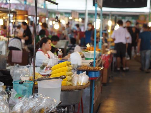 a woman sitting at a market with fruits and vegetables at 28 Place in Bangkok