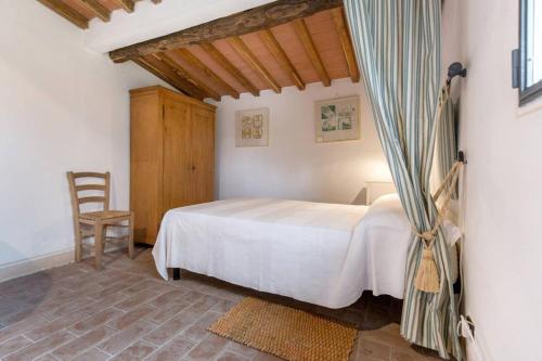 a bedroom with a white bed and a chair at Montefili in Greve in Chianti
