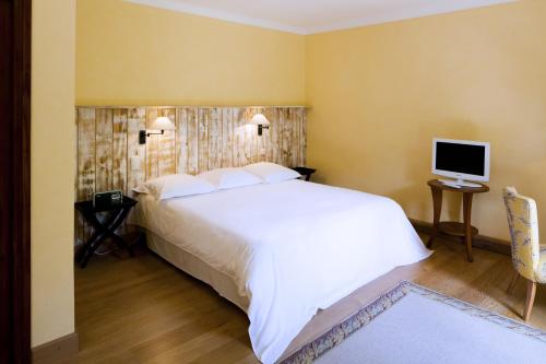 a bedroom with a large white bed and a television at Le Grand Hôtel in Molitg les Bains