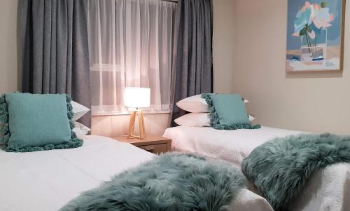 Habitación con 2 camas con cojines verdes en Rose Apartments Unit 3 Central Rotorua - Accommodation & Spa, en Rotorua