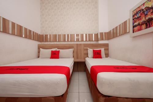 two beds in a small room with red pillows at RedDoorz near Plaza Simpang Lima in Semarang