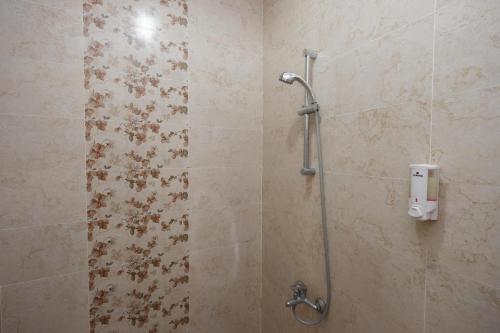 a shower in a bathroom with a tile wall at RedDoorz near Plaza Simpang Lima in Semarang