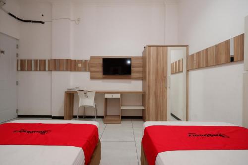 a room with two beds and a desk in it at RedDoorz near Plaza Simpang Lima in Semarang