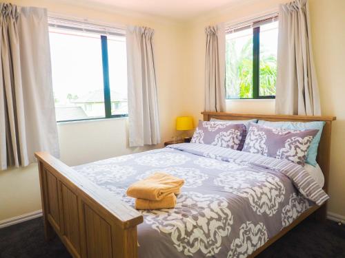 a bedroom with a bed and two windows at Accommodations Homestay in Rototuna, Hamilton in Hamilton