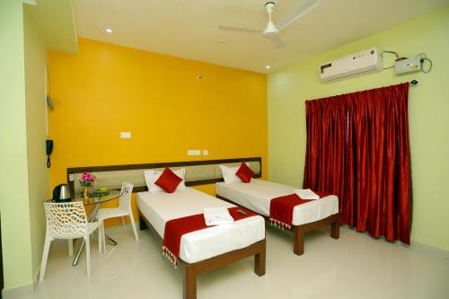 a bedroom with two beds and a table and a red curtain at Sumi Palace Annexure in Vallam