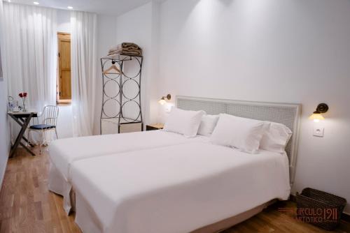 a white bedroom with a large white bed with white pillows at Círculo Artístico 1911 Hotel Boutique in Caravaca de la Cruz