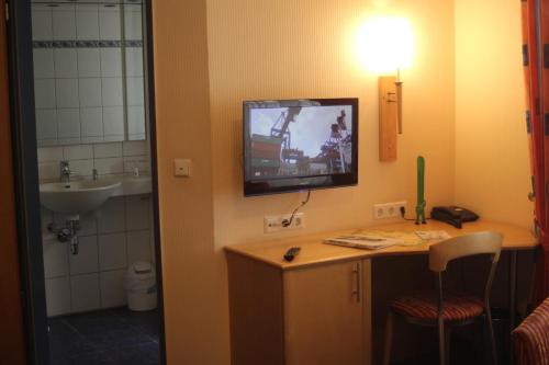 a bathroom with a sink and a tv on the wall at Akzent Hotel Hubertus in Melle