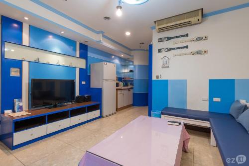 sala de estar con paredes azules, sofá y TV en Migo House en Kaohsiung