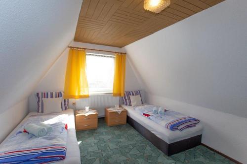 a bedroom with two beds and a window with yellow curtains at Zum Lachsfischer in Schaprode