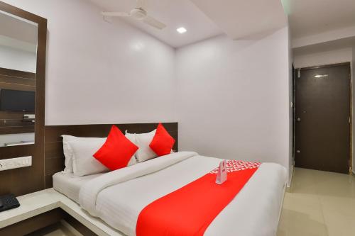a bedroom with a large bed with red pillows at Hotel Sunrise in Ahmedabad