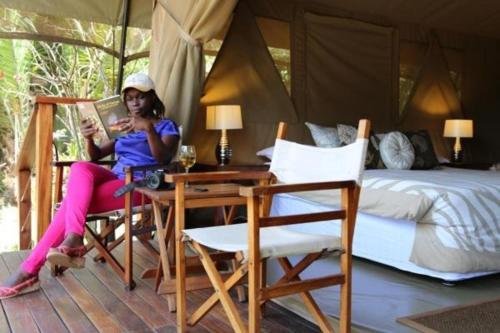 Wildebeest Eco Camp في نيروبي: امرأة تجلس على طاولة في غرفة النوم