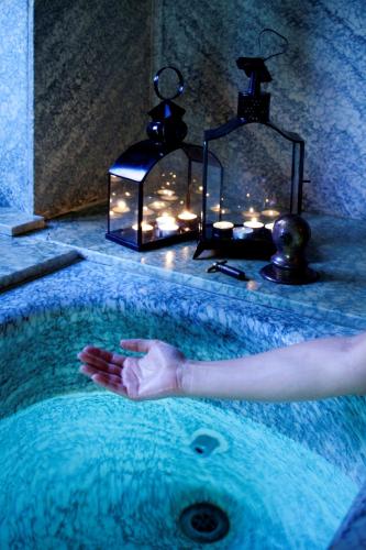a person in a bathtub with candles and a lantern at Le Grand Hôtel in Molitg les Bains