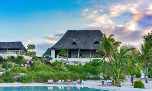 un complejo con piscina y casa en Zanbluu Beach Hotel, en Kiwengwa