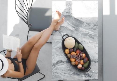 a woman with her legs up on a table with a bowl of fruit at Phos The Boutique in Akrotiri