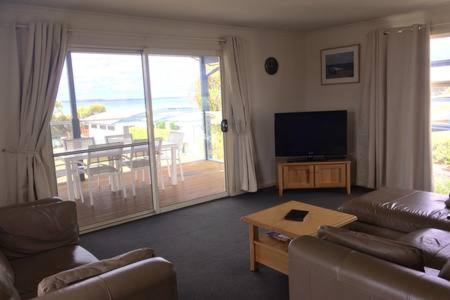 a living room with a couch and a television at Bayview Beach House Apartment No 1 in Kingscote