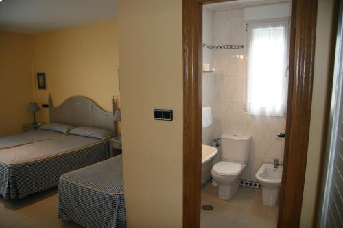 a bathroom with a bed and a toilet and a sink at Hotel Pineda Playa in Noja