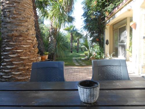 - une table avec deux chaises et un vase dans l'établissement Maison Monica Exeptionnel-Jardin paysage ZEN, à Coursan