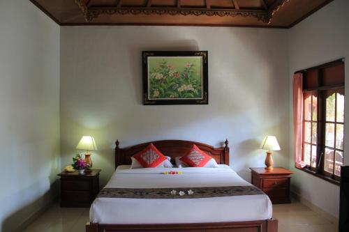 a bedroom with a large bed with red pillows at Stana Puri Gopa Hotel in Sanur
