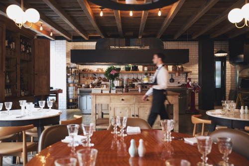 a man walking in a restaurant with tables at Rooms Hotel Tbilisi in Tbilisi City