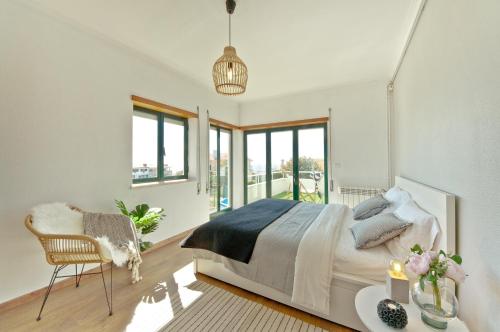 um quarto com uma cama, uma cadeira e janelas em Casa da Légua em Moledo