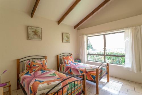 2 Betten in einem Zimmer mit Fenster in der Unterkunft Mango Cottage in Rarotonga