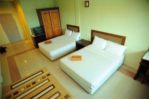 a hotel room with two beds and a television at Arwana Inn Tok Bali in Pasir Puteh