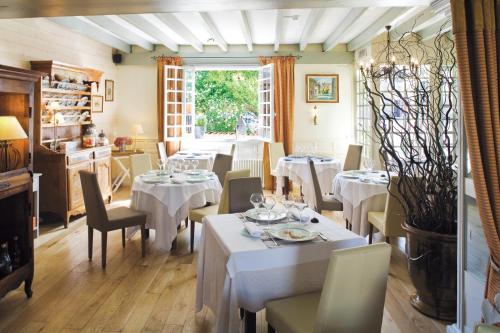 een restaurant met witte tafels en stoelen en een raam bij Logis Le Central in Coulon