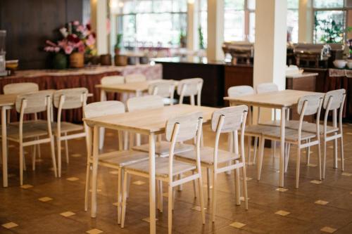 a group of wooden tables and chairs in a restaurant at Diamond Park Inn Chiangrai & Resort in Chiang Rai