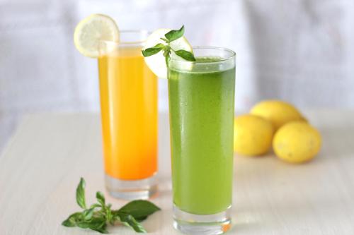 two glasses of green and orange juices on a table at Three Eight Front One Boutique Batu Malang in Batu