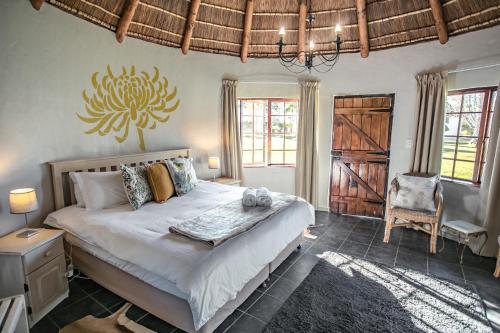 a bedroom with a large bed and a chair at Bella Manga Country Escape in Plettenberg Bay