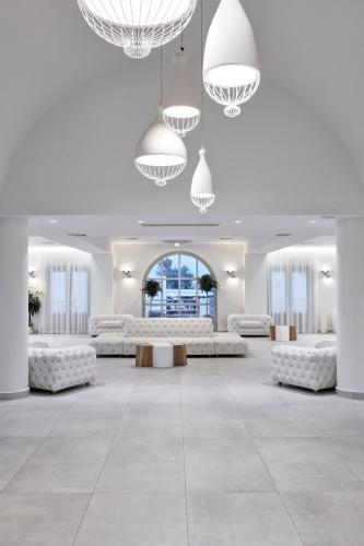 a large room with white furniture and large chandeliers at Costa Grand Resort & Spa in Kamari