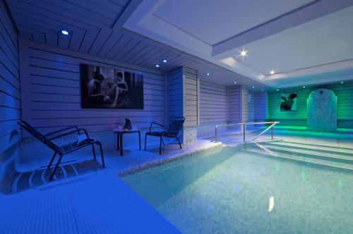 a swimming pool with two chairs and a table at Hotel Le Morgane in Chamonix-Mont-Blanc