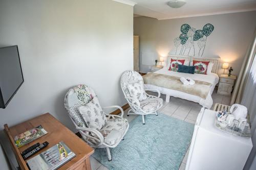 a bedroom with a bed and two chairs and a table at Bella Manga Country Escape in Plettenberg Bay