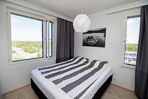 a bedroom with a bed and two large windows at Pro Apartments 1 in Vaasa