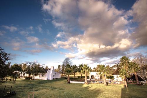 a white house with palm trees and a cloudy sky at Bella Manga Country Escape in Plettenberg Bay