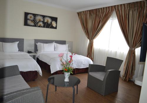 a hotel room with two beds and a table with flowers at Angsoka Hotel in Teluk Intan