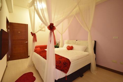 a bedroom with a canopy bed with white curtains at 世外桃園民宿 in Taitung City