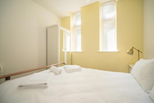 sypialnia z białym łóżkiem i 2 ręcznikami w obiekcie Marlborough Hall Majestic Apartment - Quiet w Nottingham