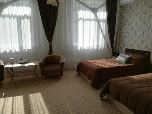 a hotel room with two beds and a chair at Hotel Bahetle in Ekibastuz