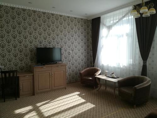 a living room with a television and a table and chairs at Hotel Bahetle in Ekibastuz