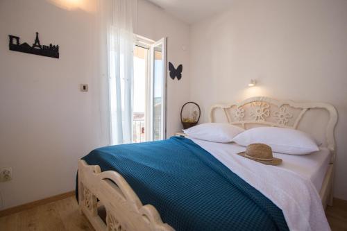 a bedroom with a white bed with a hat on it at Apartments Frenkie in Komiža