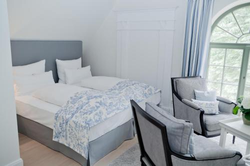 a bedroom with a bed and two chairs and a window at Landhaus Töpferhof bei Travemünde in Travemünde