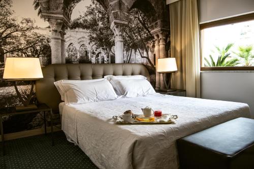 a bedroom with a bed with a tray of food on it at Hotel Federico II Central Palace in Palermo