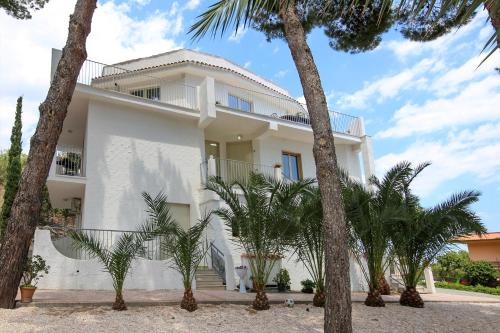 a white house with palm trees in front of it at villa aurora in Giardini Naxos