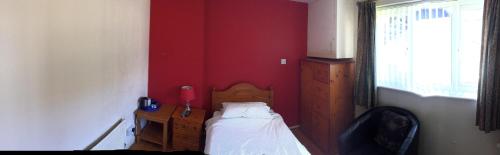 a bedroom with a bed and a red wall at Red Lion Accommodation in Abingdon