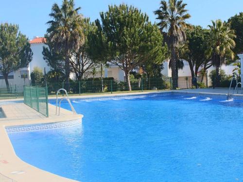 uma grande piscina azul com árvores ao fundo em Casa Hortensia em Chiclana de la Frontera