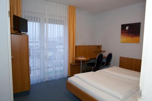 Svg Hotel Kalimera في لودفيغسهافن أم راين: غرفة فندقية بسرير وطاولة مع كراسي